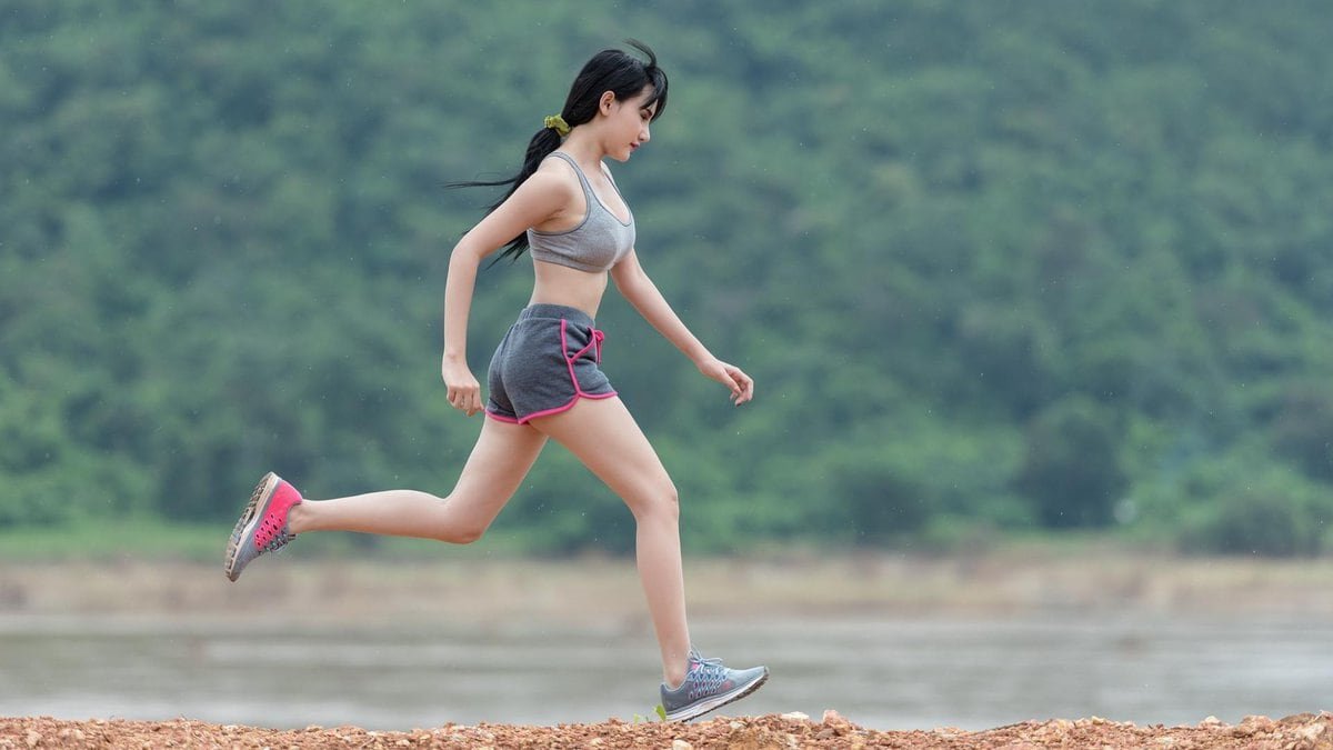 Une femme épilée qui fait du jogging près d’un plan d’eau.